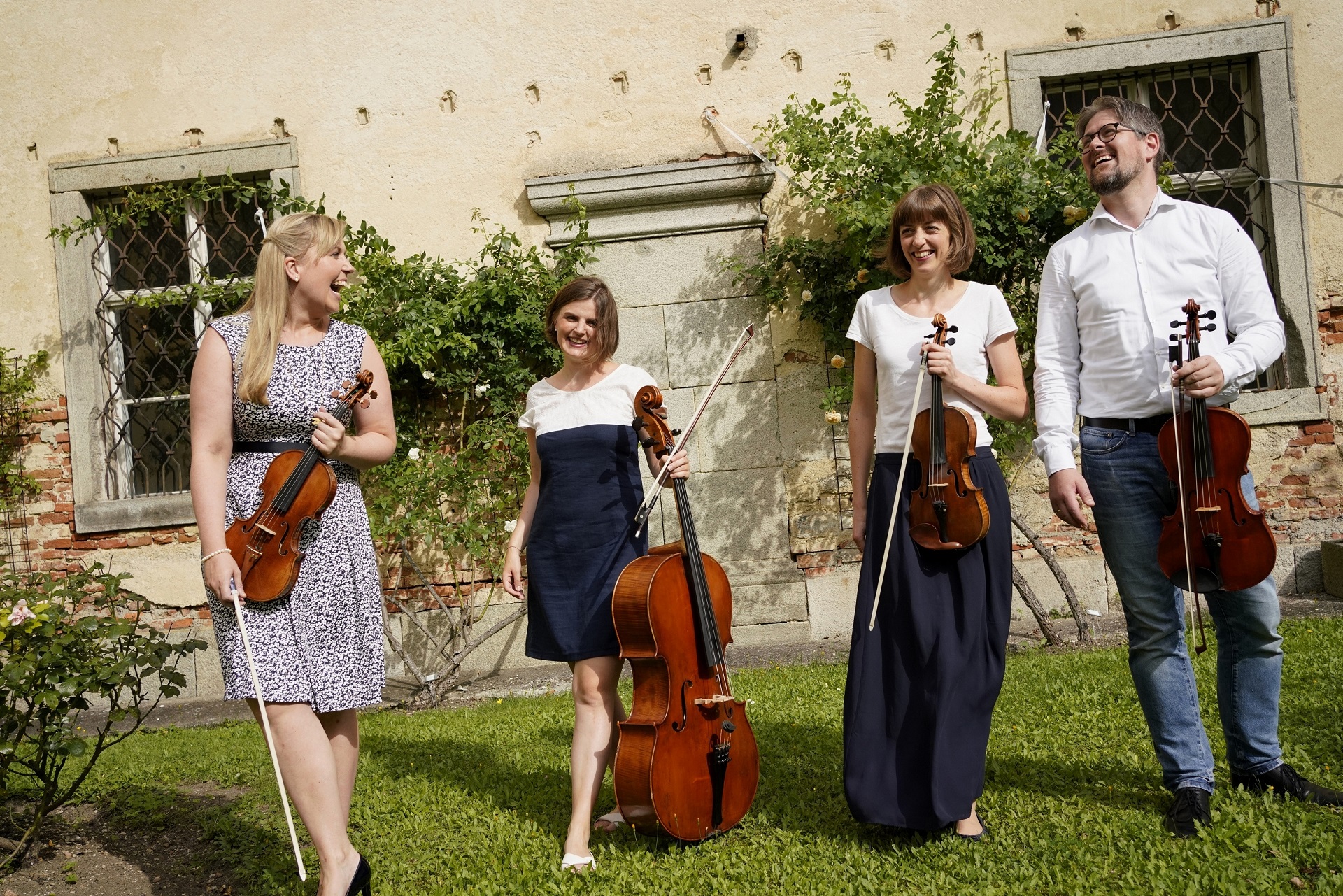 Zu sehen sind die 4 Musiker des Atalante Quartetts in einem Garten vor einem alten Gebäude.